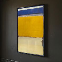 an abstract painting hangs on the wall in a room with dark walls and white flooring