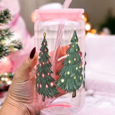 a hand holding a glass with christmas trees on it