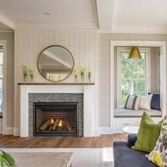 a living room filled with furniture and a fire place under a mirror on the wall