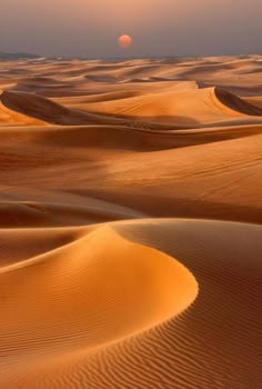 the sun is setting over sand dunes in the sahara desert, with no people on it