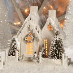 a christmas scene with a lit up house in the snow