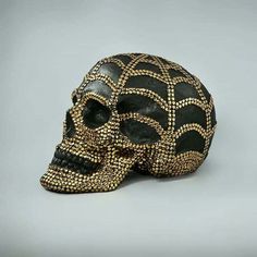 a black and gold skull is shown on a gray background with an intricately designed pattern