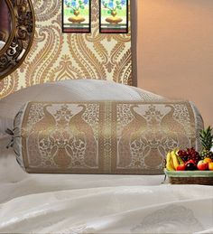 a bed with a tray of fruit on top of it next to a wallpapered headboard