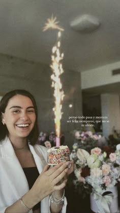 a woman holding a cake with sprinkles on it