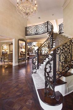 an elegant staircase with wrought iron railing and chandelier