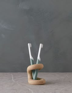 two toothbrushes in a holder made out of cork