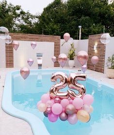 balloons floating in the air next to a pool with a number twenty balloon decoration on it