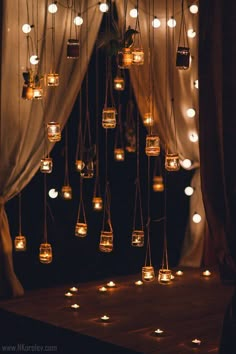 a room with candles hanging from the ceiling and drapes on the wall, filled with lights