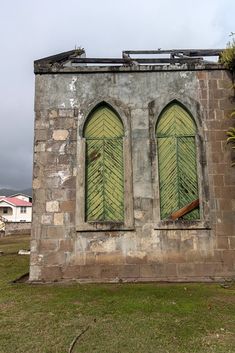 an old building with two green windows on the front and one window in the back