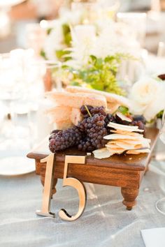 a wooden table topped with grapes and cheese