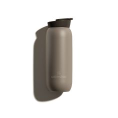 a gray water bottle sitting on top of a white wall