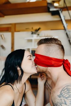 a man and woman kissing each other with a red ribbon on their forehead, in front of a staircase