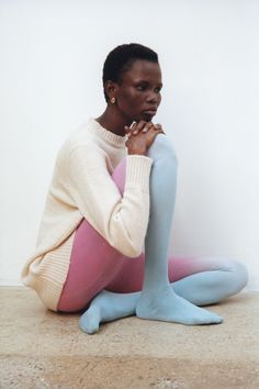 a woman sitting on the ground with her legs crossed wearing blue and pink tights