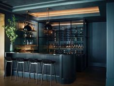 a bar with several stools and bottles on the wall behind it in a dark room