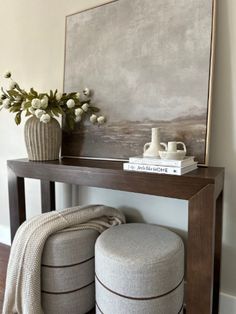 a table with two stools and a painting on the wall