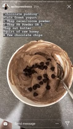 a bowl filled with chocolate pudding on top of a counter next to a hand holding a spoon