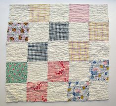 a patchwork quilt is displayed on a white surface with pink, blue and green squares