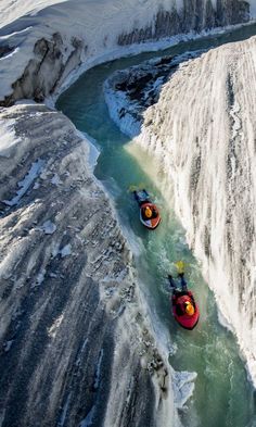 two people are kayaking down a river in the snow