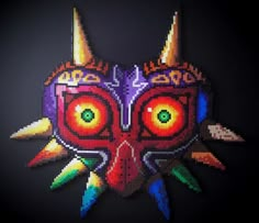 an image of a mask made out of pixelated beads on a black background with red eyes and yellow horns