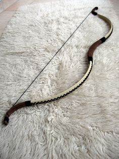 an archery bow laying on top of a fluffy white rug in the middle of a room