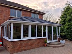 a brick house with white windows and a tiled patio