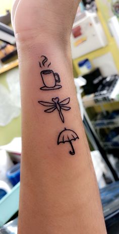 a person with a tattoo on their arm has an umbrella and coffee cup in it