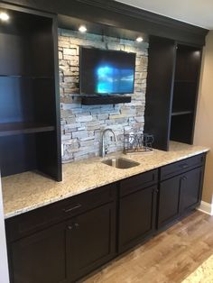 a kitchen with black cabinets and a flat screen tv mounted on the back of it