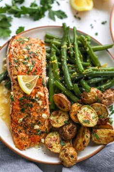 salmon, potatoes and green beans on a plate with lemon wedged garnish