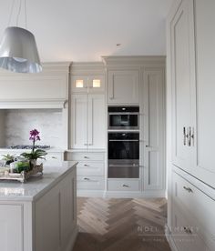 a large kitchen with white cabinets and an island in the middle is lit by pendant lights