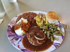 a plate with beans, mashed potatoes, green beans, and bread on it