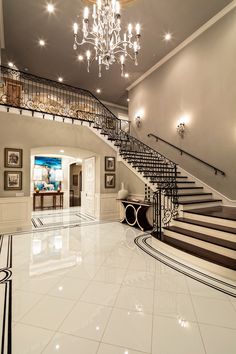 an elegant staircase with chandelier and marble flooring in a large foyer area