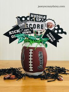 a football centerpiece with black and white decorations in it on top of a wooden table