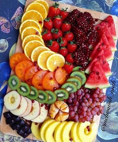 a wooden cutting board topped with lots of fruit