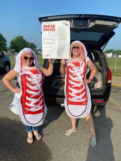 two women in red and white converse shoes holding up a shoe drive sign while standing next to a car