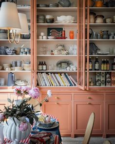 a dining room table with plates and bowls on it, next to an open bookcase