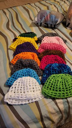 there are many crocheted hats on the bed