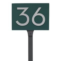 a green and white house number sign on a metal pole