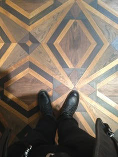 a person standing on top of a wooden floor next to a black bag and shoes