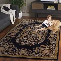 a young boy sitting on top of a rug next to a dog