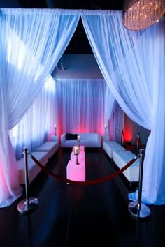 a room decorated with white drapes and pink couches, candles and chandeliers