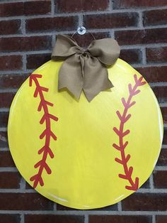 a yellow sign with a brown bow on it that has a baseball ball painted on it