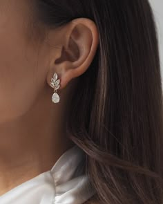 a close up of a woman's ear wearing a pair of earrings with leaves on them