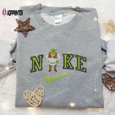 Introducing the Nike x Shrek Embroidered Sweatshirt, a collaboration that brings together the iconic Nike style and the beloved Shrek Shrek Cartoon, Nike Inspired, Custom Sweaters, Nike Style, Cartoon Shirts, Cartoon Sweatshirts, Shirt Nike, Nike Brand, 3d Shirt