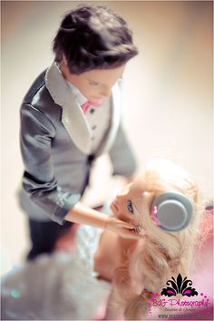 a barbie doll is standing next to a man in a tuxedo and headphones