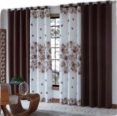 a living room with white curtains and brown flowers on the drapes, along with a coffee table