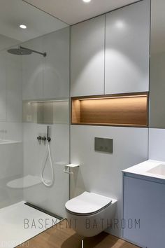 a modern bathroom with white walls and wood flooring, including a glass enclosed shower stall