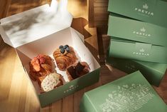 three green boxes with pastries in them sitting on a wooden table next to each other