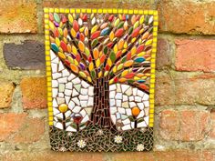 a colorful mosaic tree on a brick wall