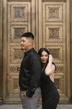 a man and woman standing next to each other in front of a gold door with intricate carvings