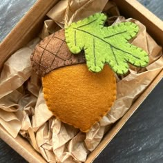 an orange with green leaves in a cardboard box